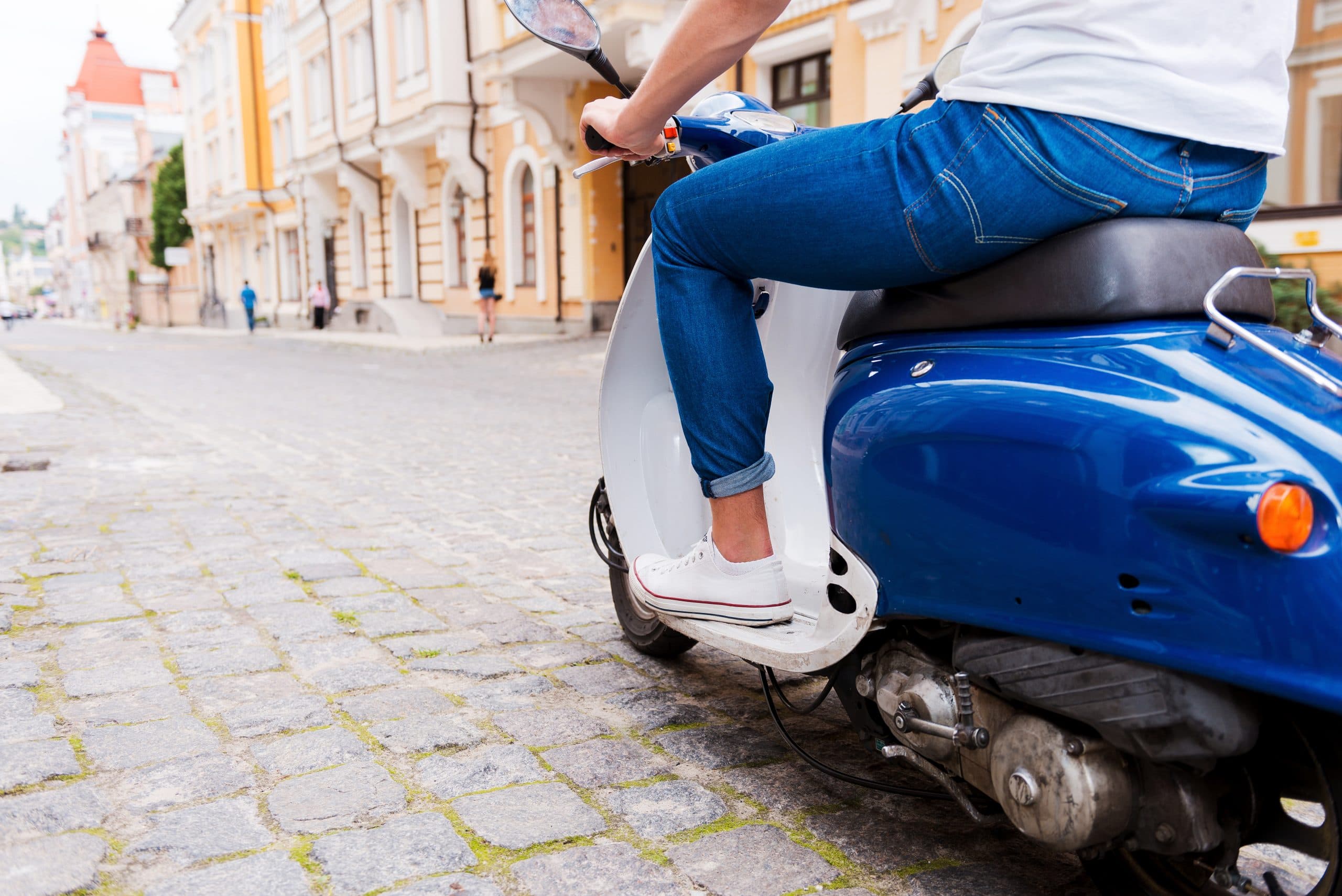 Conducteur sur Vespa le long de la route côtière de Stintino, ciel dégagé sur la mer sarde